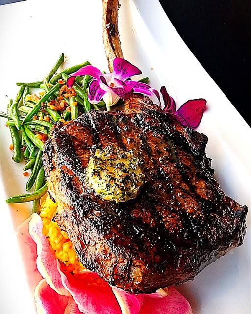 Chef Ryan Baker's bone-in ribeye with herb butter, green beans & orchid garnish — CityWalk Eatery Cedar Rapids